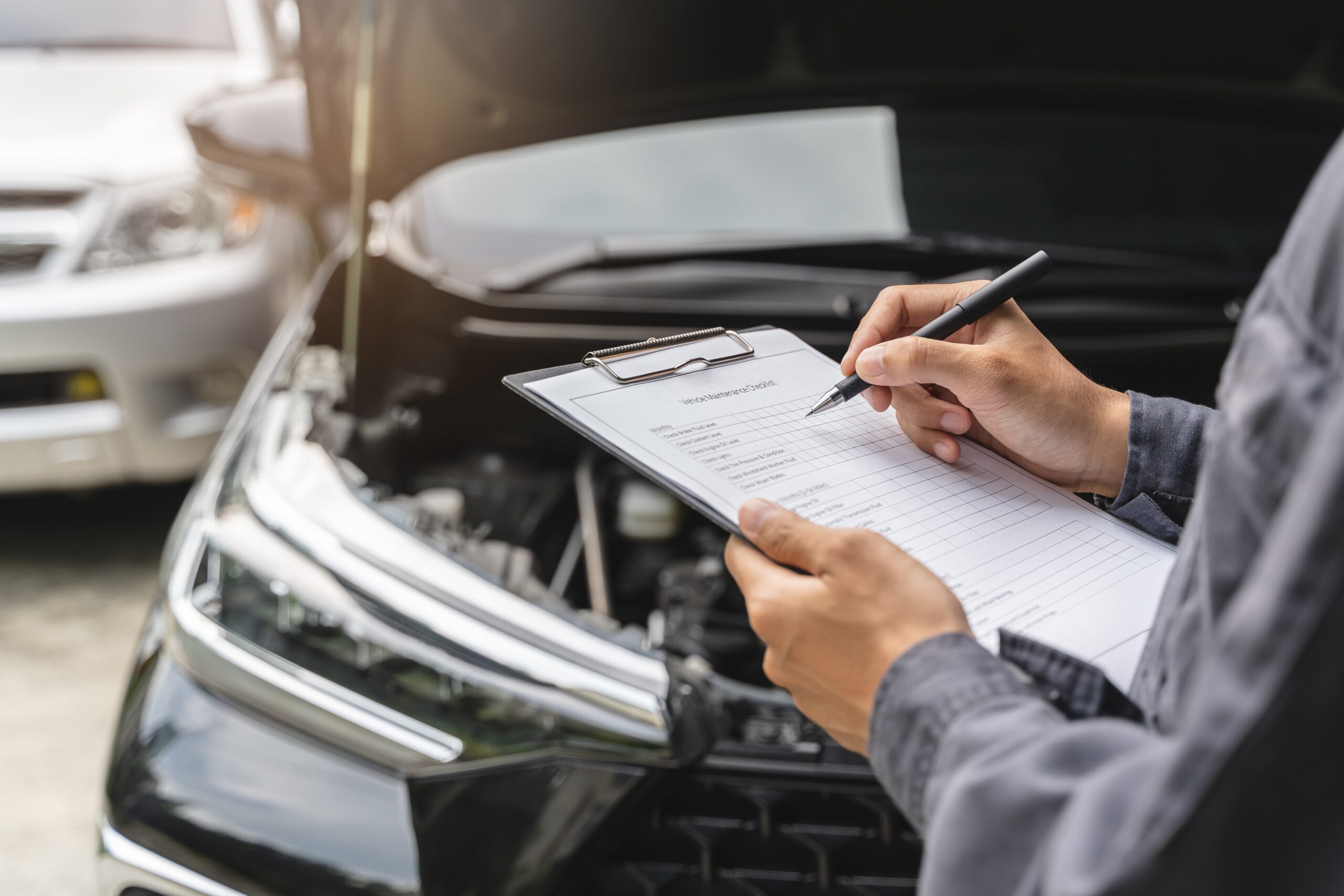 Mechanic inspecting car with checklist.