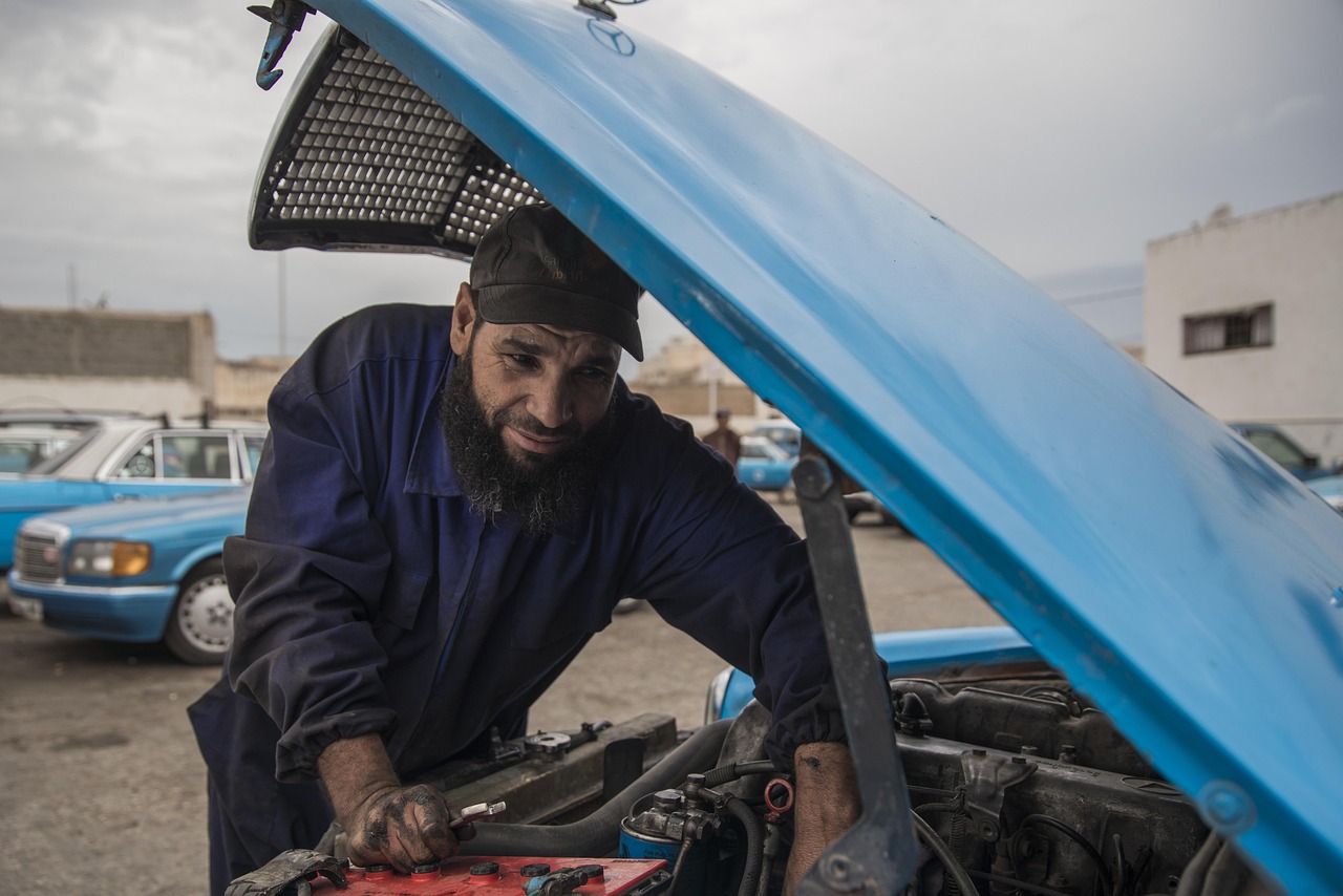 Vehicle tester entering roadworthy test result at a computer terminal with car visible on hoist through office window